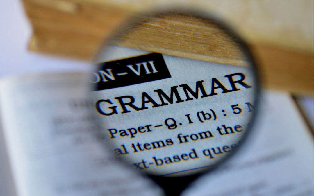 magnifying glass hovering over the word "grammar" in a dictionary